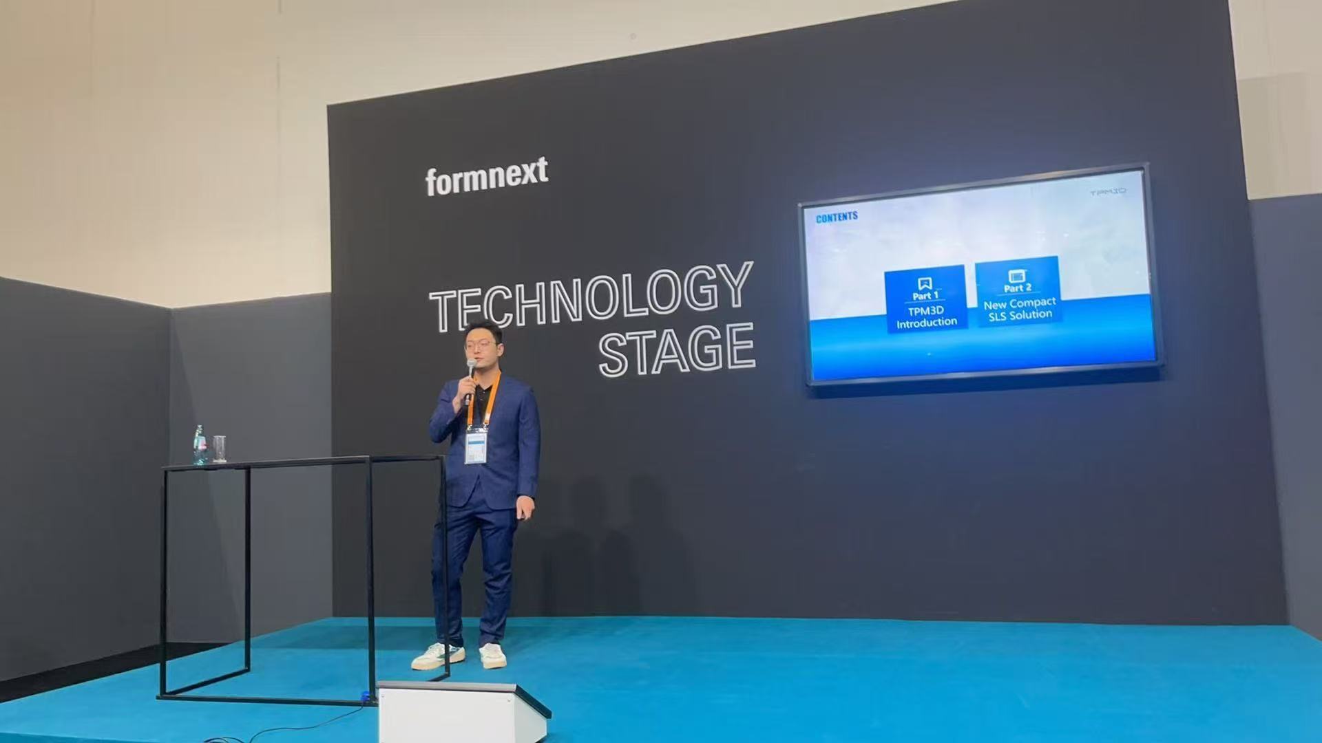 Engenheiro de aplicações da TPM3D apresentando a impressora SLS compacta CF200 no palco de tecnologia da Formnext.
